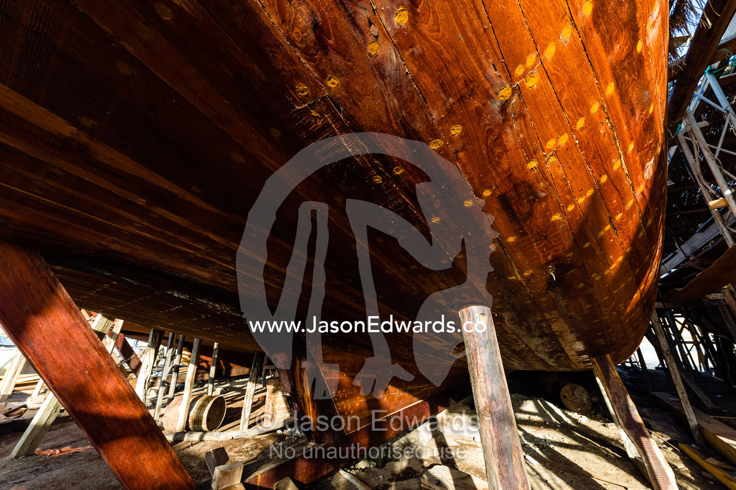 Nail holes filled with putty and freshly oiled timber hull planks on a dhow under construction. Sur, Ash Sharqiyah Region, Gulf of Oman, Sultanate of Oman.