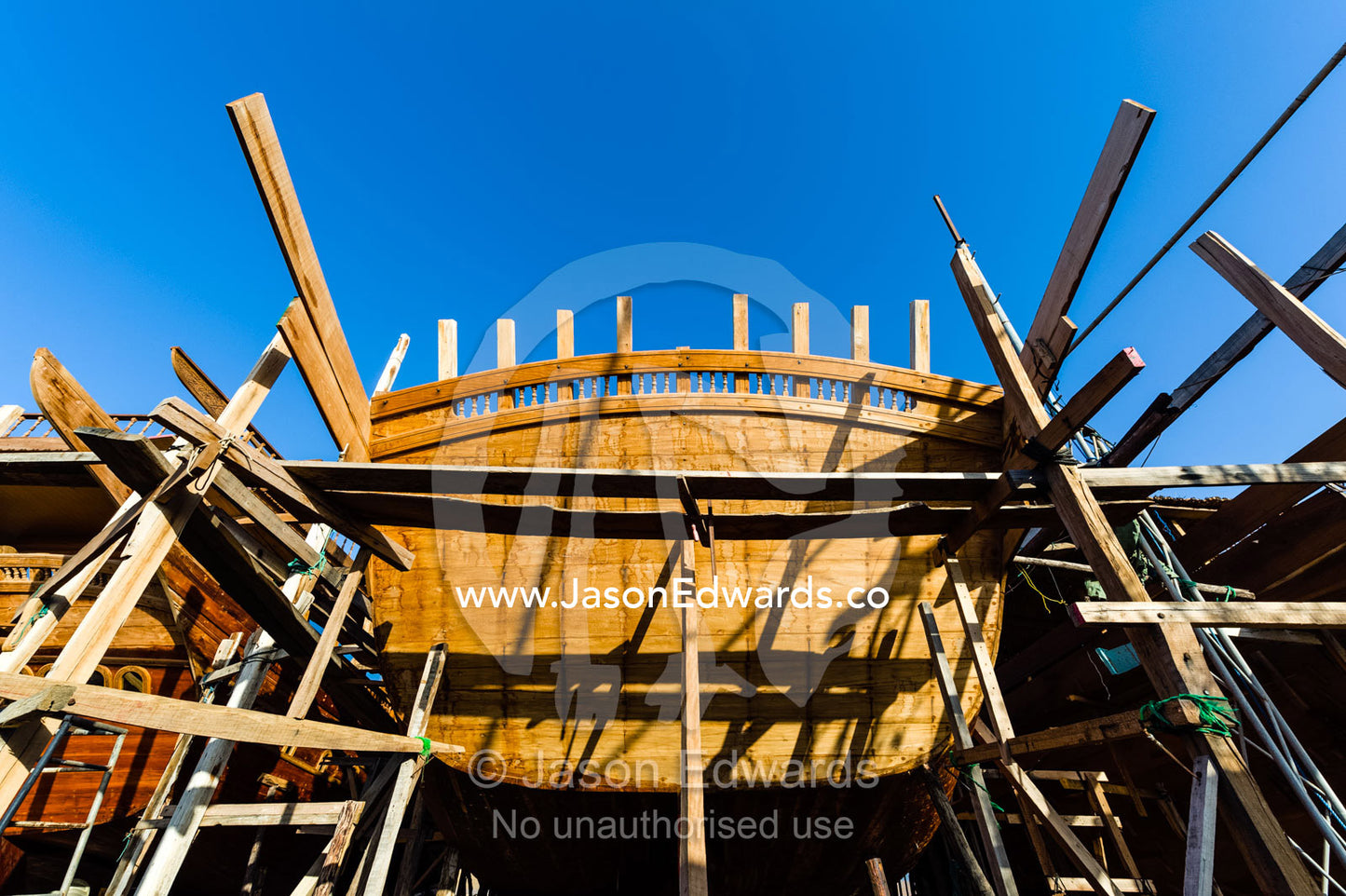 Timber and steel scaffolding supports the hull during handmade construction of an ancient timber dhow. Sur, Ash Sharqiyah Region, Gulf of Oman, Sultanate of Oman.