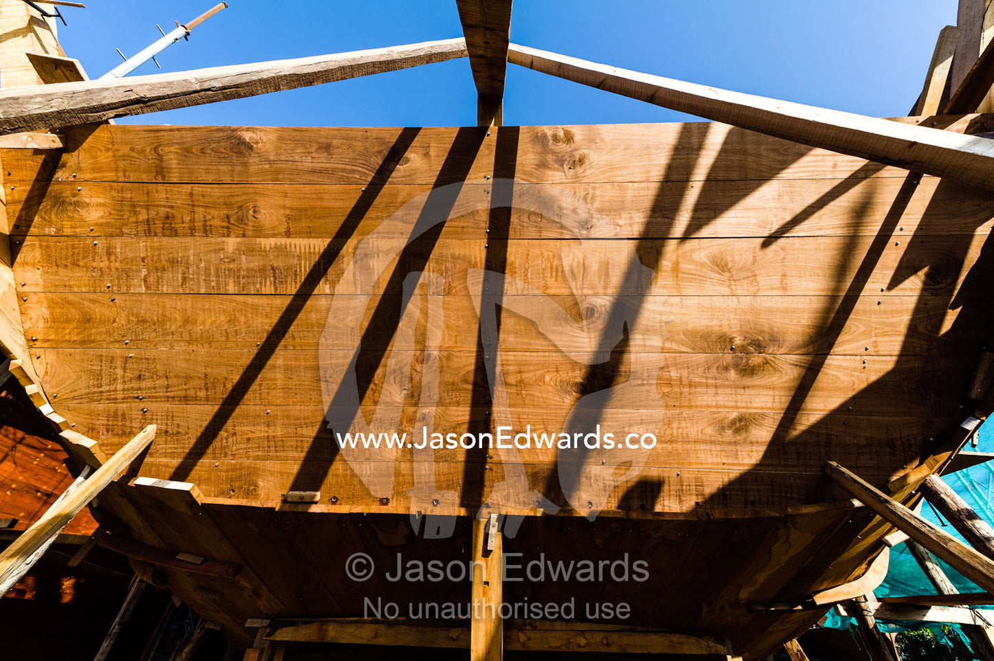 Scaffolding supports the hull and stern during handmade construction of an ancient timber dhow. Sur, Ash Sharqiyah Region, Gulf of Oman, Sultanate of Oman.
