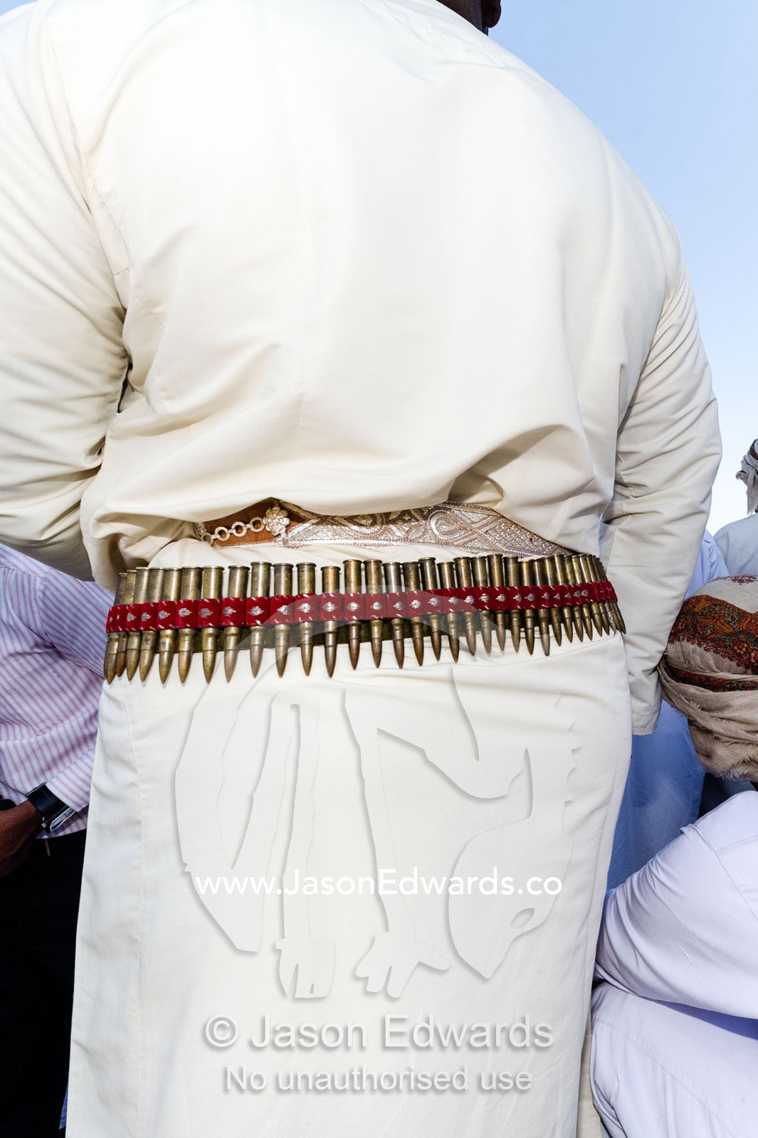 A bandolier of bullets decorates the waist belt of a di dash at a camel race event. Bidiya, Sharqiya Region, Sultanate of Oman.