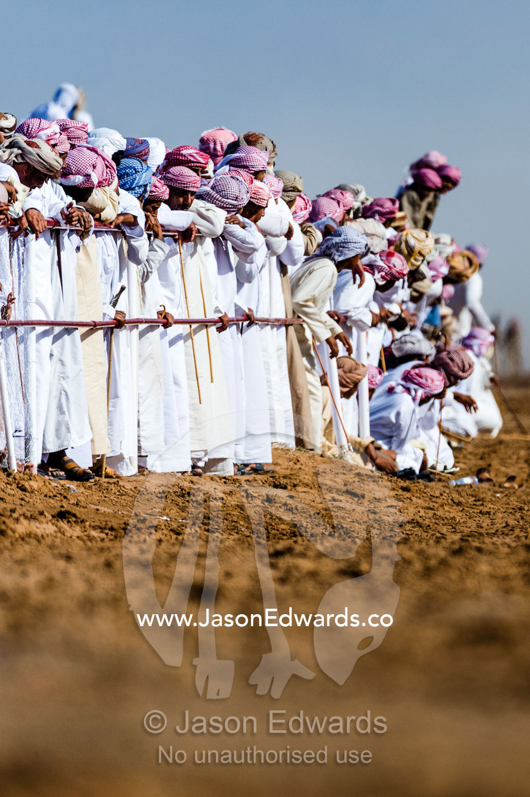 A crowd of Muslim men wearing dishdasha and masar gather to watch camel races. Bidiya, Sharqiya Region, Sultanate of Oman.