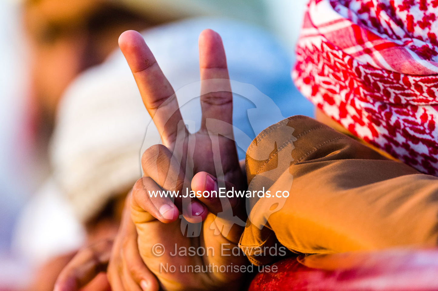 A Muslim teenager gives the Peace sign with his fingers during a camel race in the desert. Bidiya, Sharqiya Region, Sultanate of Oman.