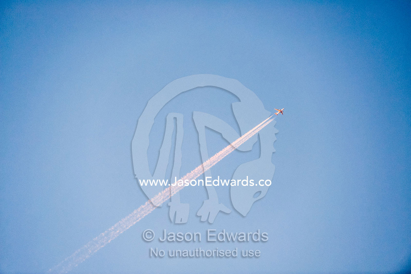 The jet stream vapor of a passenger jet turns pastel pink in the dawn sunlight. Wahiba Sands, Ramlat al-Wahiba, Sharqiya Sands, Sultanate of Oman.