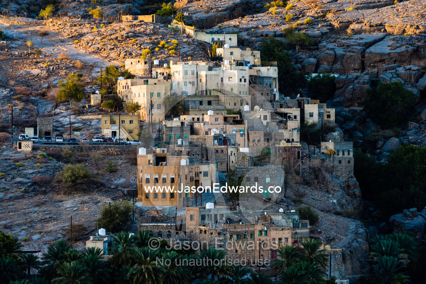 An ancient mud brick village on a desert gorge mountainside surrounded by palm trees. Misfat Al Abryeen, Al Hajar Mountains, Al Hamra, Ad Dakhiliyah Region, Sultanate of Oman.