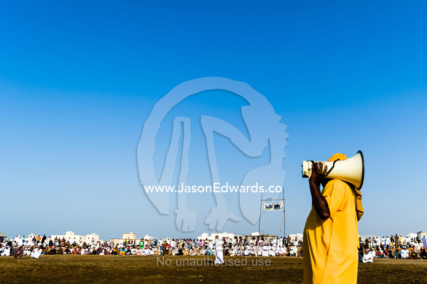 An comedian with a megaphone entertains the crowd at a traditional bullfight. Al Sharadi, Seeb, Muscat, Sultanate of Oman.