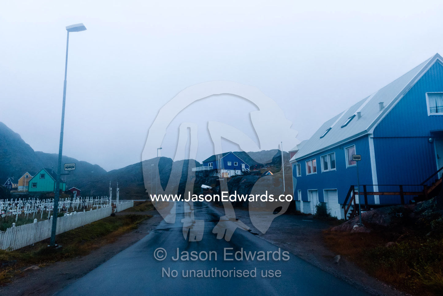 Evening descends over a wet road running through a fishing village. Maniitsoq, Sukkertoppen, Qeqqata Municipality, Greenland.