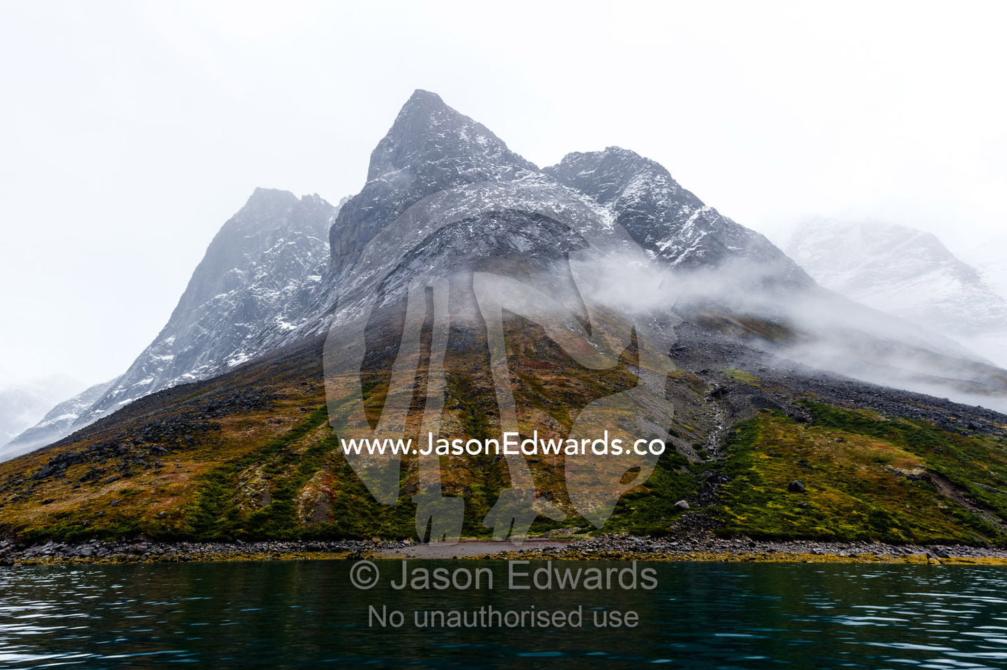 Cloud and mist shroud jagged and rugged mountain peaks during a rain storm in a fiord. Fjord of Eternity, Maniitsoq, Sukkertoppen, Qeqqata Municipality, Greenland.