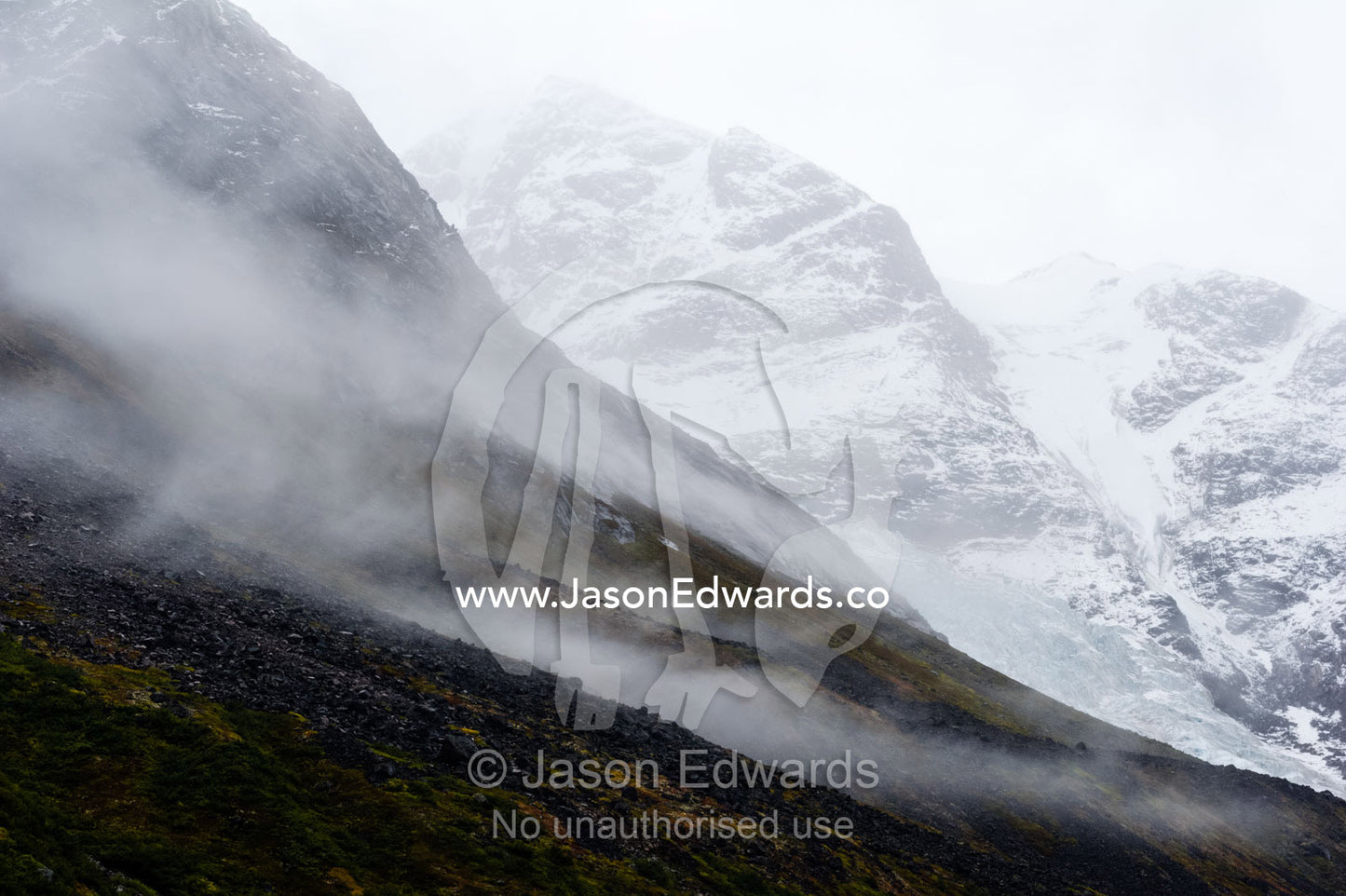 Cloud and mist shroud jagged and rugged mountain peaks during a rain storm in a fiord. Fjord of Eternity, Maniitsoq, Sukkertoppen, Qeqqata Municipality, Greenland.