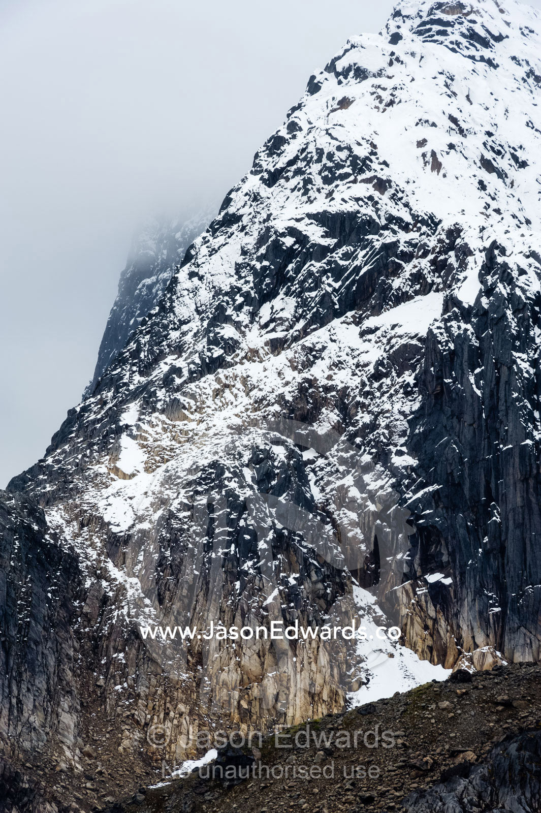The snow and ice covered cliff face of a rugged mountain. Fjord of Eternity, Maniitsoq, Sukkertoppen, Qeqqata Municipality, Greenland.