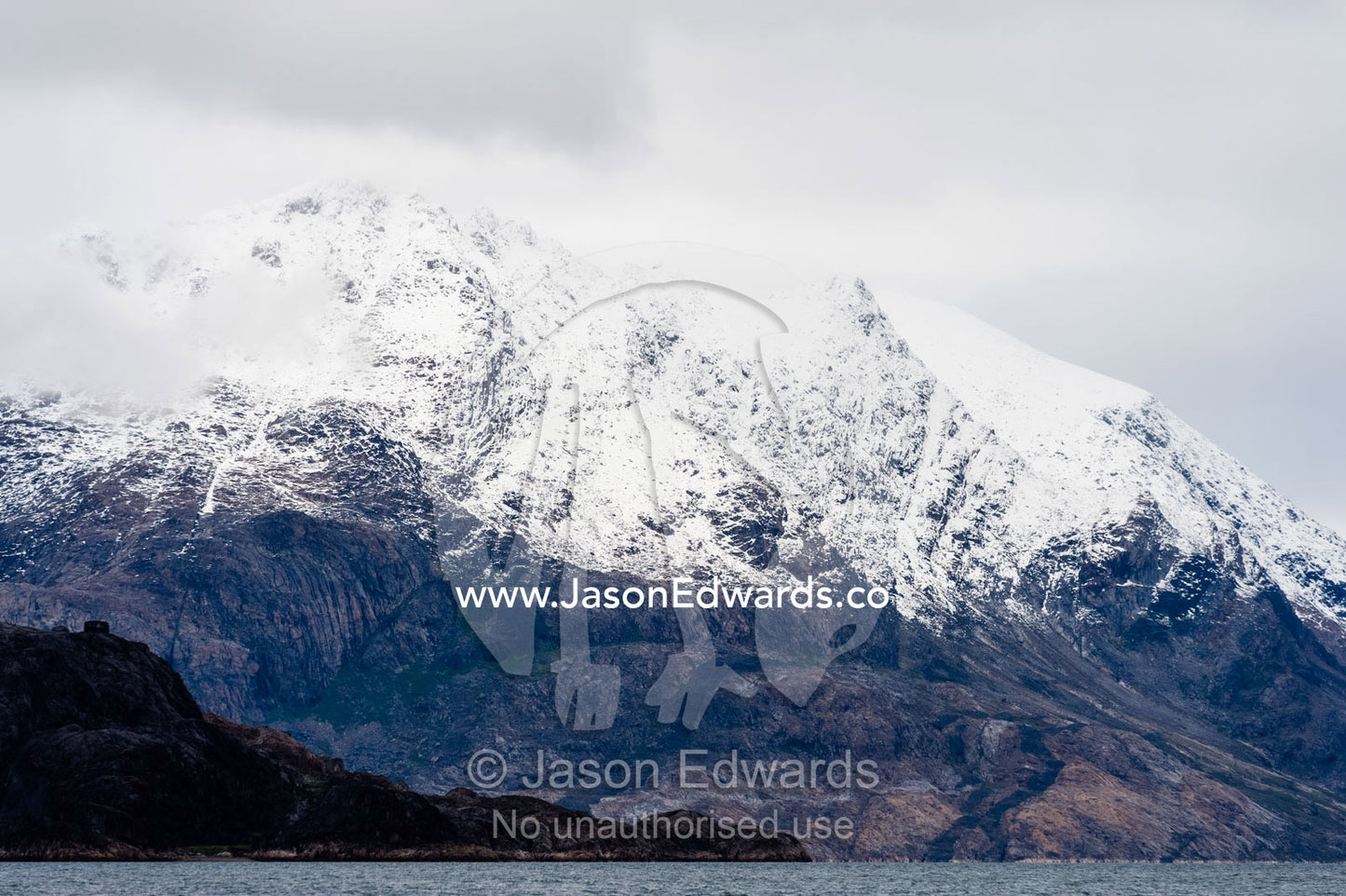 The snowline of a mountain range above an arctic fjord. Fjord of Eternity, Maniitsoq, Sukkertoppen, Qeqqata Municipality, Greenland.