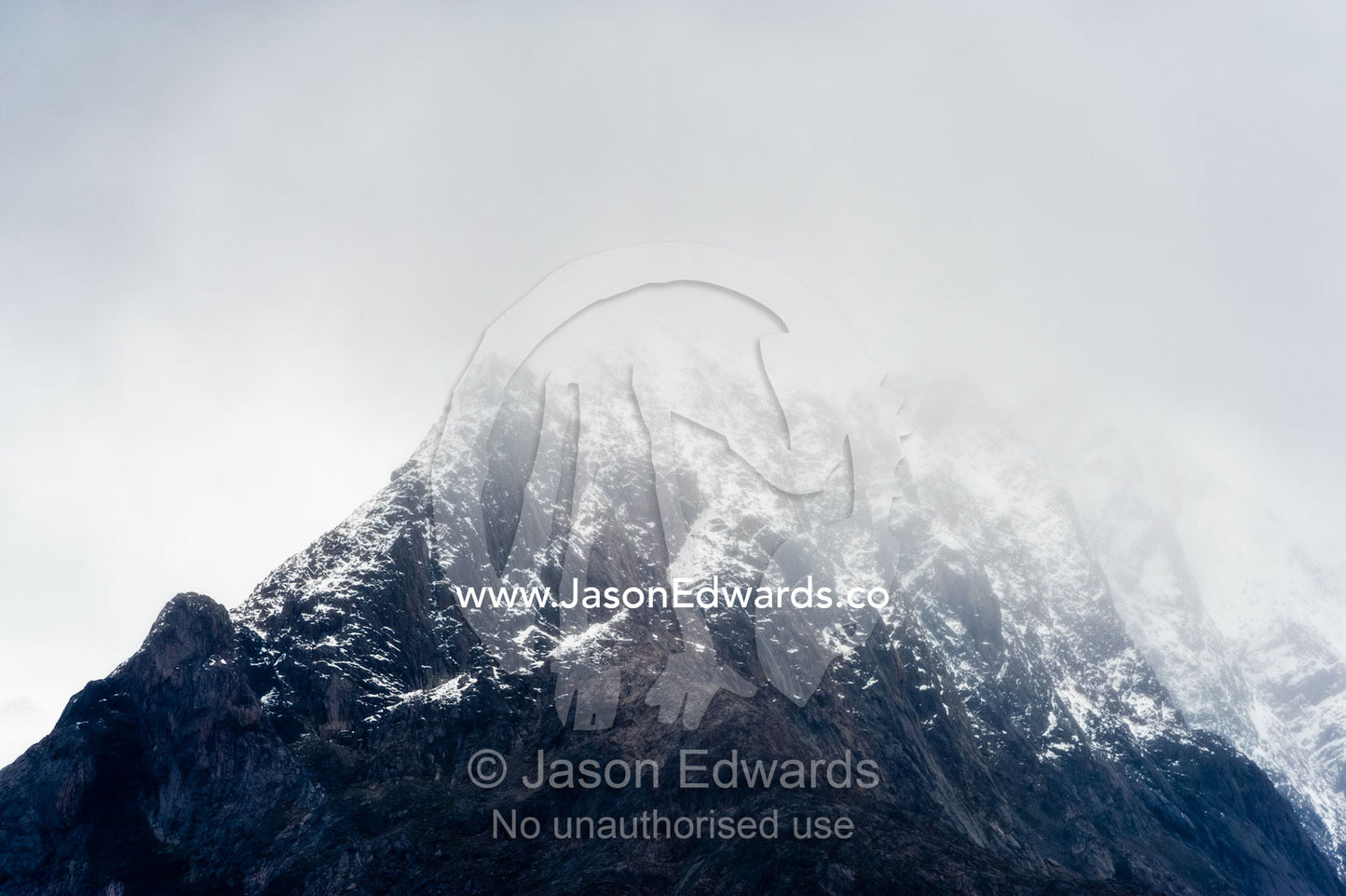 Clouds descending on the snowy summit of a jagged mountain range. Davis Strait, Fjord of Eternity, Maniitsoq, Sukkertoppen, Qeqqata Municipality, Greenland.