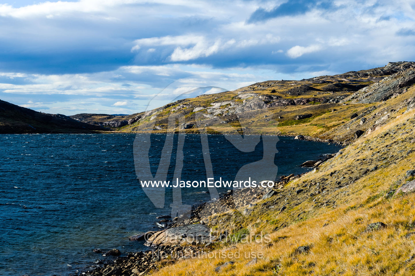 The shoreline and low rolling tundra hills surrounding an alpine lake. Isunngua Highland, Kangerlussuaq, Qeqqata Municipality, Greenland.