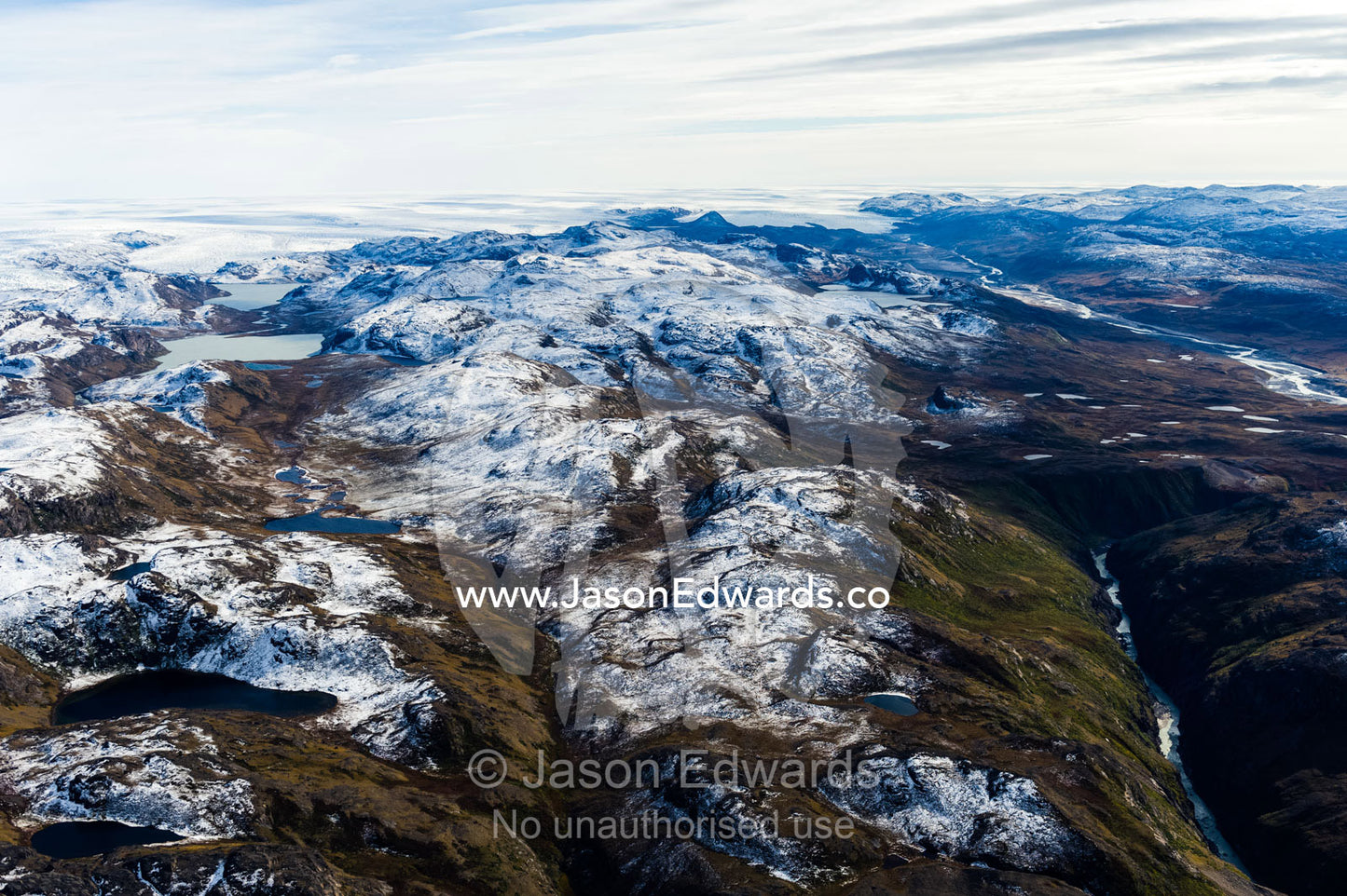 A dusting of snow covers mountain peaks on a highland tundra plateau. Tarajornitsut Highlands, Qeqqata Municipality, Kangerlussuaq, Greenland.