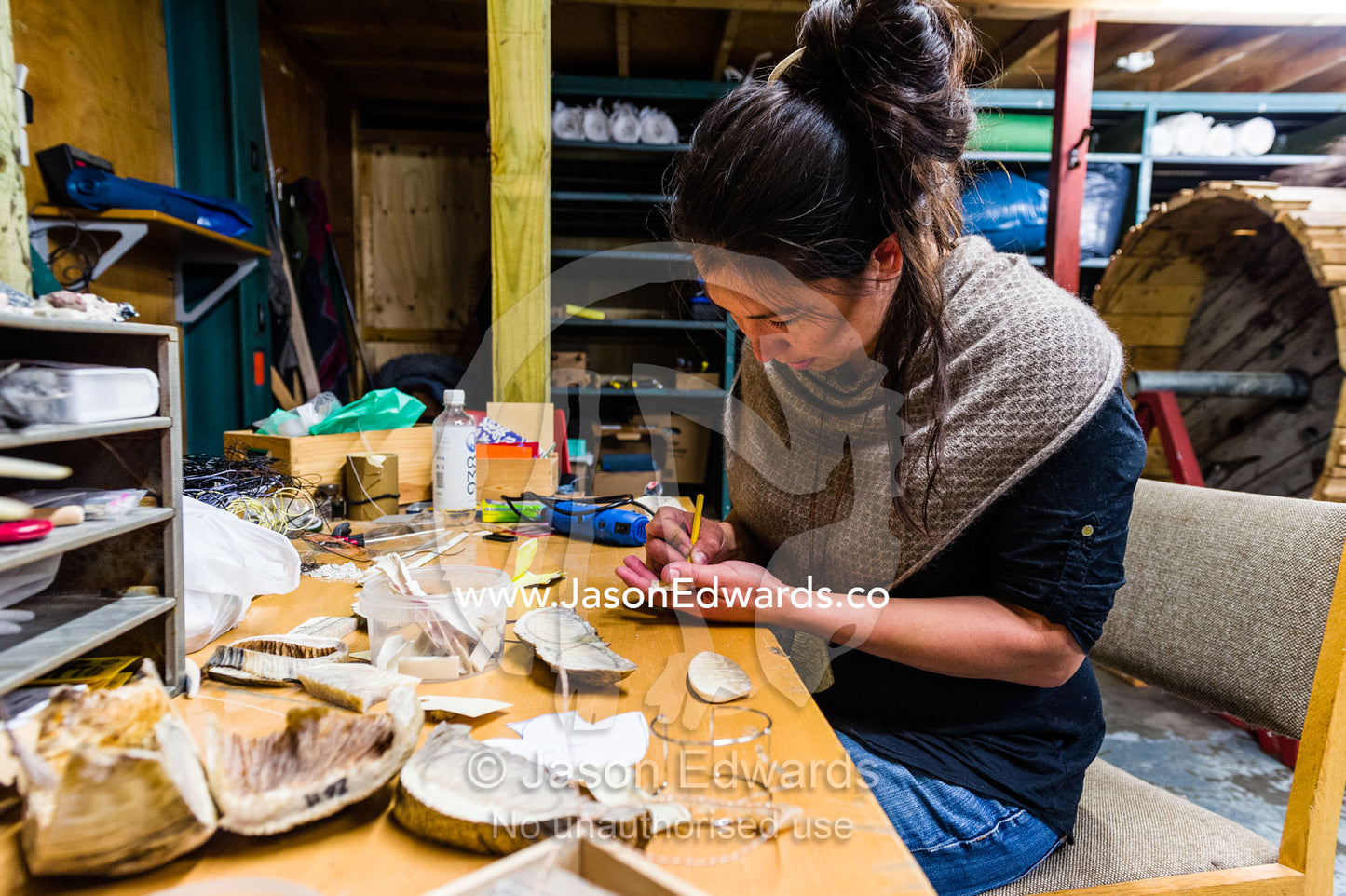 An artist carving jewelry from Musk Ox horns in her studio. Kangerlussuaq, Qeqqata Municipality, Greenland.
