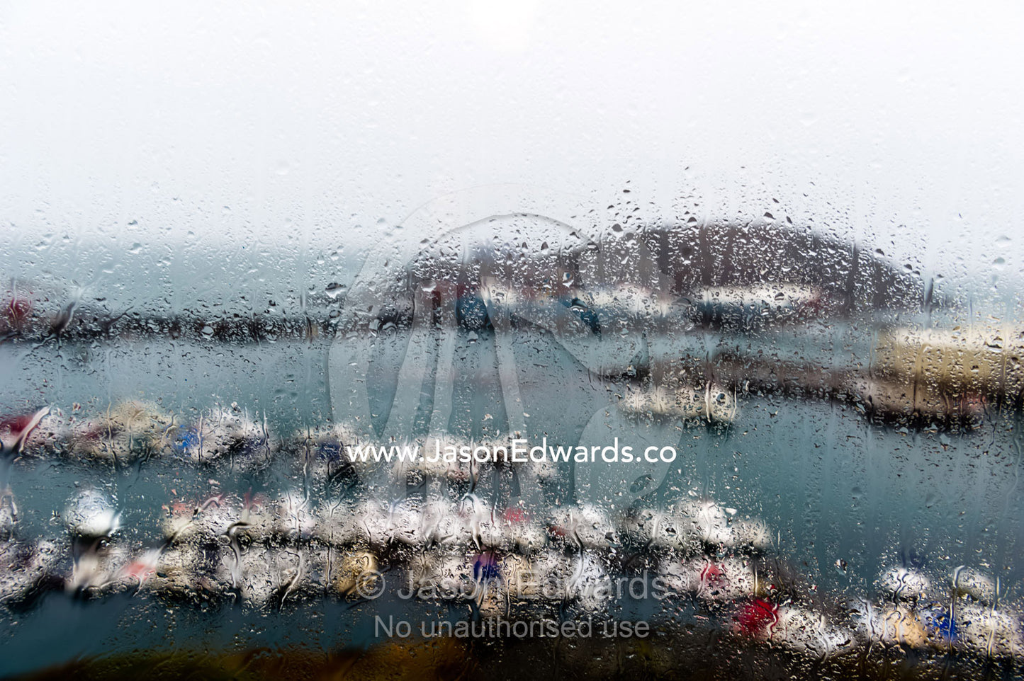 A rain storm lashing a window overlooking a fishing boat harbor. Maniitsoq, Sukkertoppen, Qeqqata Municipality, Greenland.