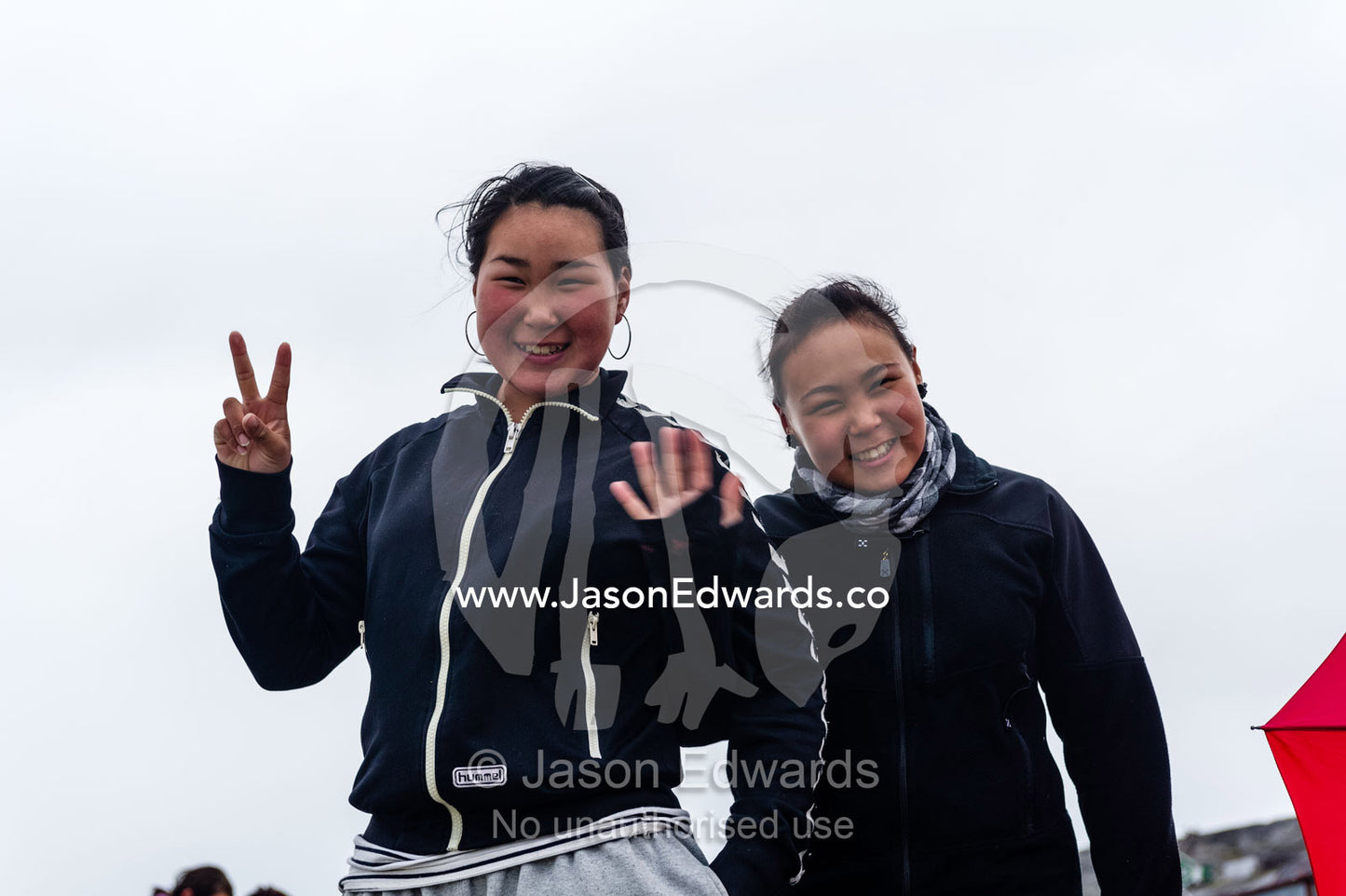 Teenage girls on an arctic island waving goodbye. Kangaamiut, Gammel Sukkertoppen, Qeqqata Municipality, Greenland.