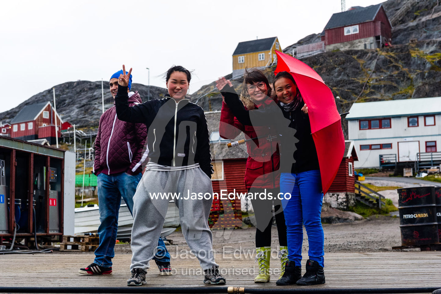 Teenage school students and their teacher wave goodbye from a dock on an arctic island. Kangaamiut, Gammel Sukkertoppen, Qeqqata Municipality, Greenland.