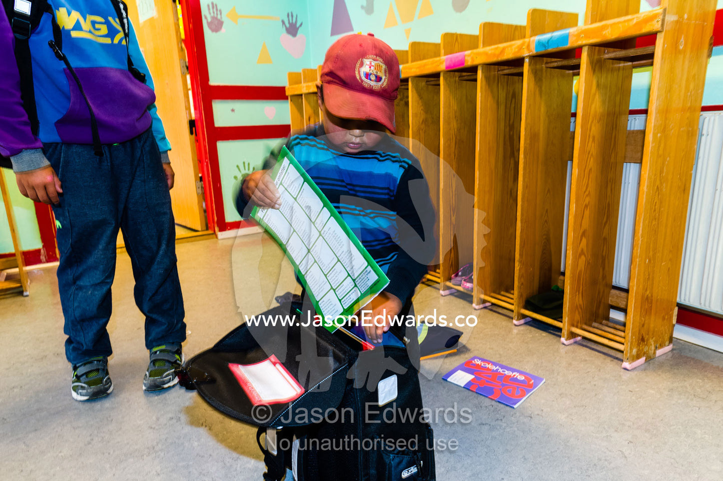 A small boy placing his books in a school bag at the end of the day. Kangaamiut, Gammel Sukkertoppen, Qeqqata Municipality, Greenland.
