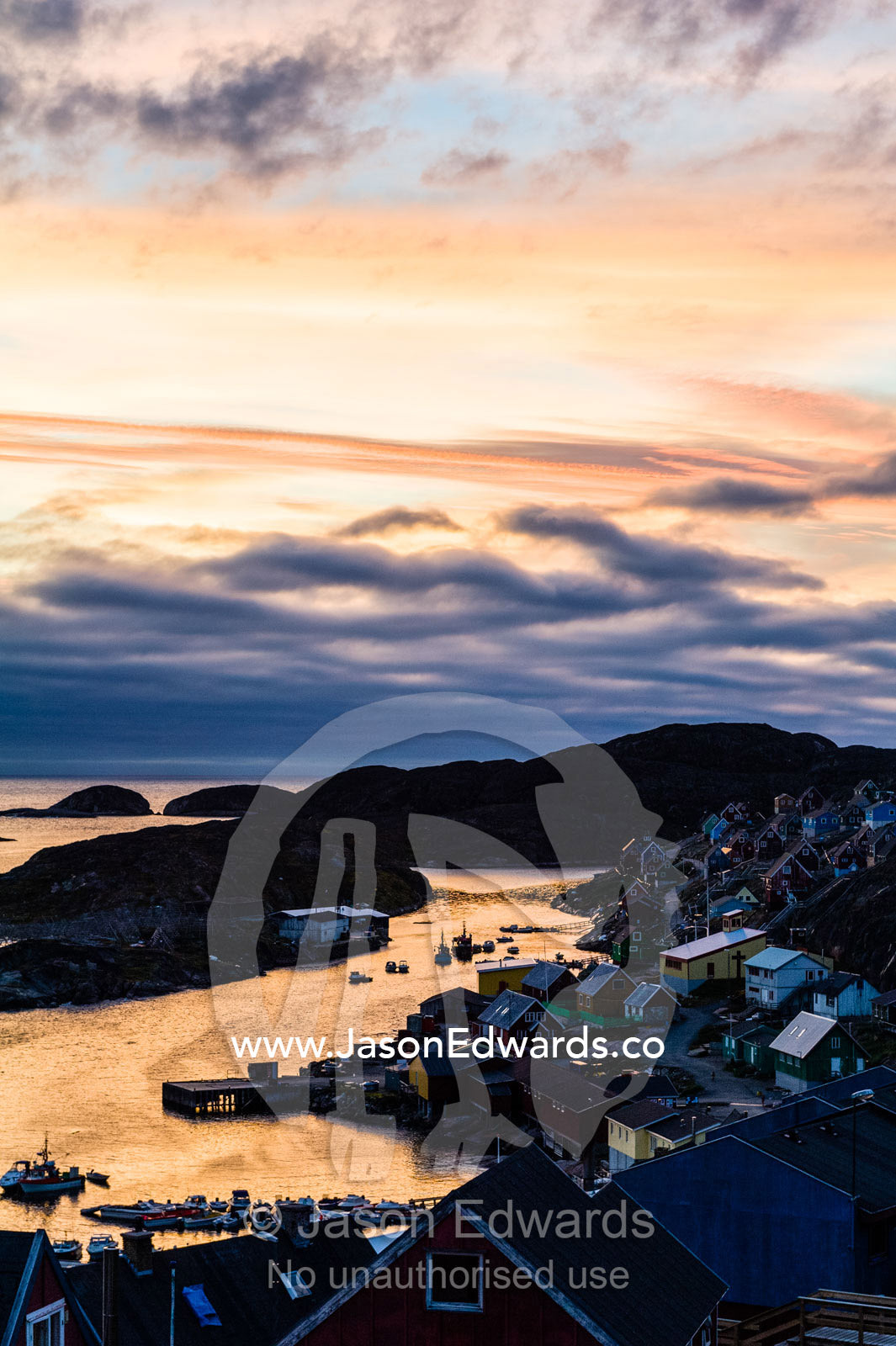 Sunset falls over an arctic fishing village on a rugged island. Davis Strait, Kangaamiut, Gammel Sukkertoppen, Qeqqata Municipality, Greenland.