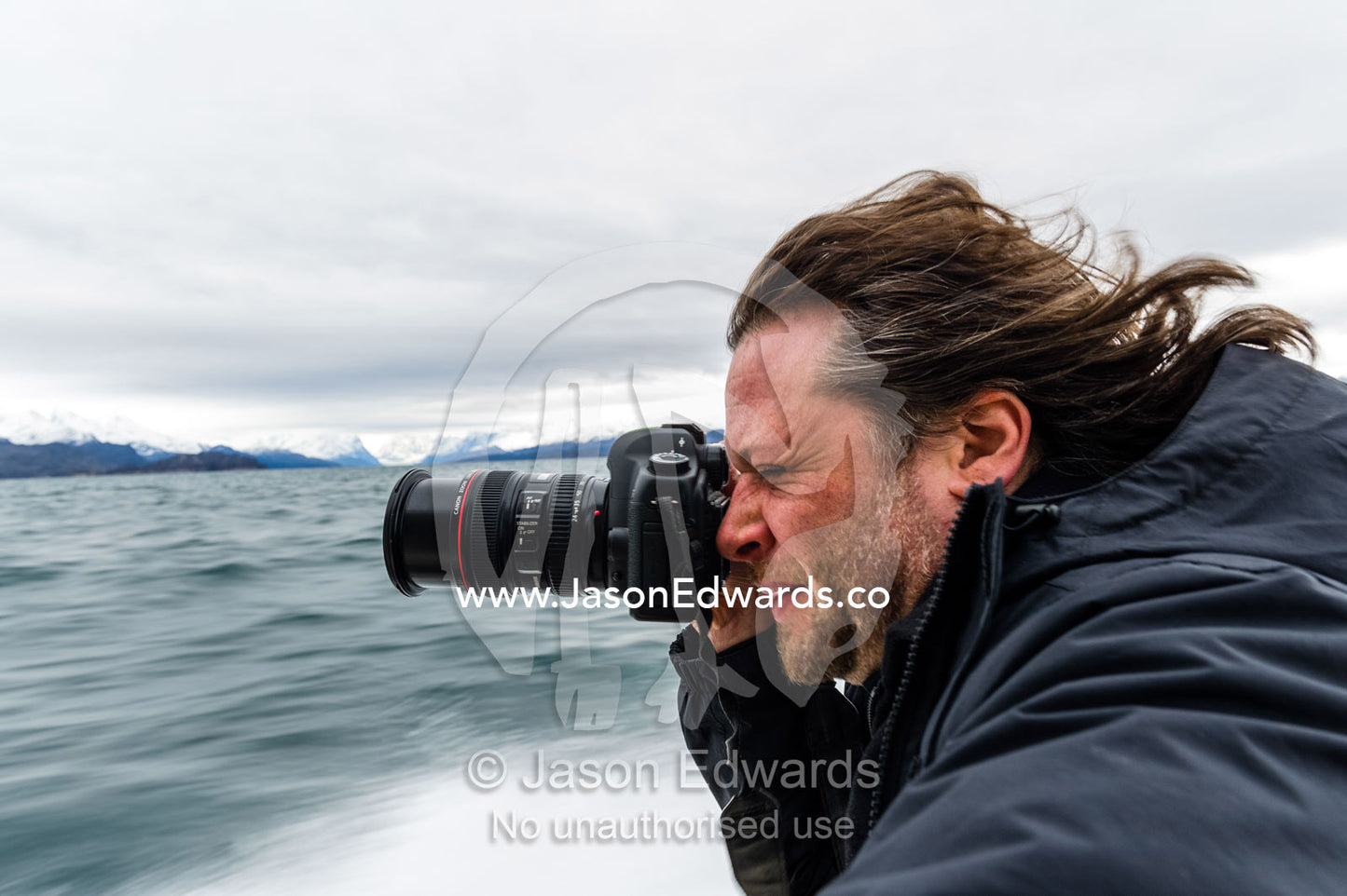 A man takes a photo from a speeding boat as it races across the ocean. Davis Strait, Kangaamiut, Gammel Sukkertoppen, Qeqqata Municipality, Greenland.