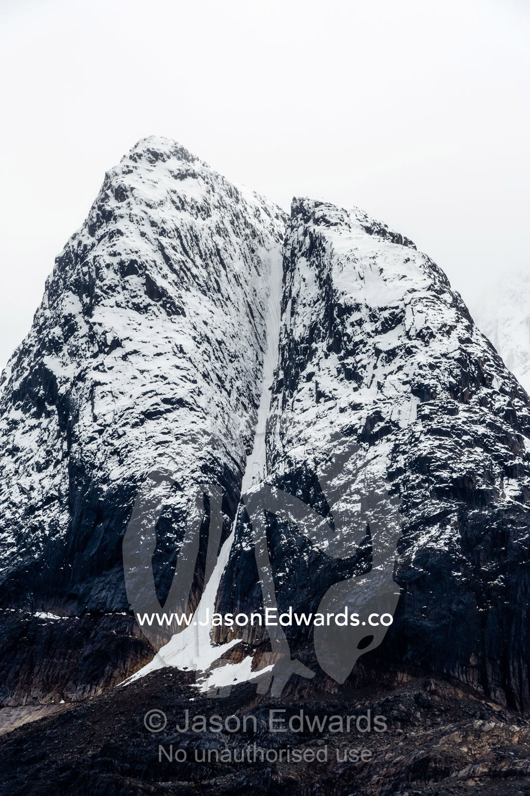 A rugged cone-shaped mountain summit dusted in snow and ice. Davis Strait, Fjord of Eternity, Maniitsoq, Sukkertoppen, Qeqqata Municipality, Greenland.