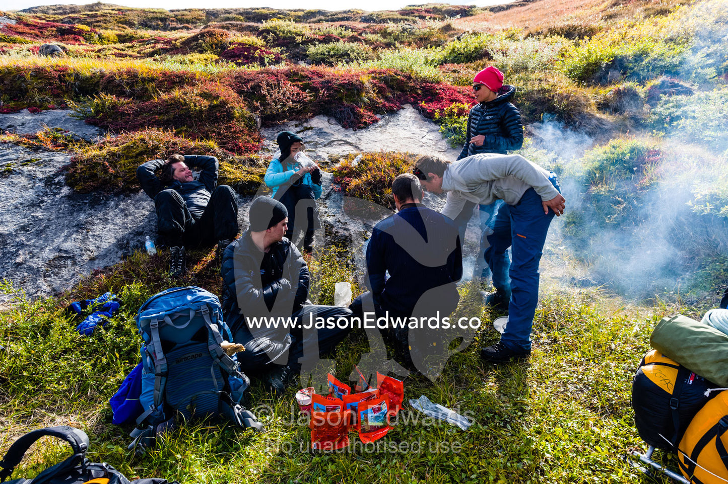 Hikers preparing lunch on a small fire on the arctic tundra. Ammalortup Nunaa Highland, Kangerlussuaq, Qeqqata Municipality, Greenland.