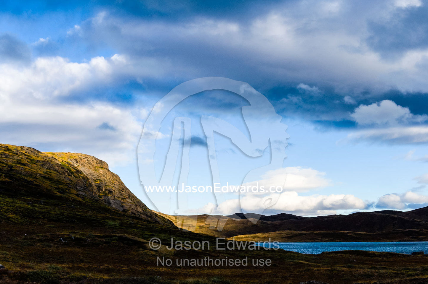 Sunset touches the summit of a mountain overlooking an alpine lake. Ammalortup Nunaa Highland, Kangerlussuaq, Qeqqata Municipality, Greenland.