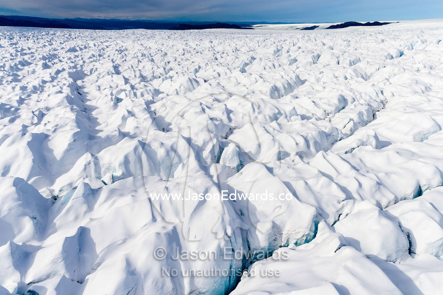 Layers of snow mask deep crevasse on the surface of the vast Greenland Ice Sheet plain. Greenland Ice Sheet, Qeqqata Municipality, Kangerlussuaq, Greenland.