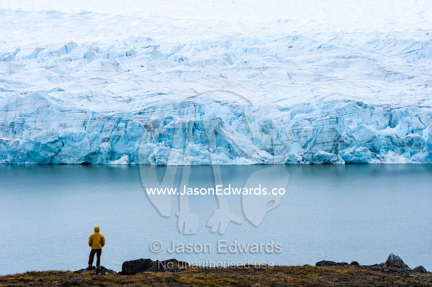 A hiker dwarfed by the fracture zone of a glacier on the Greenland Ice Sheet. Isunngua Highland, Greenland Ice Sheet, Kangerlussuaq, Qeqqata Municipality, Greenland.