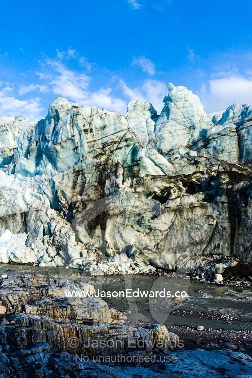 Erosion from ice against rock deposits silt and soil sediment on the face of a glacier fracture zone. Russell Glacier, Greenland Ice Sheet, Qeqqata Municipality, Kangerlussuaq, Greenland.