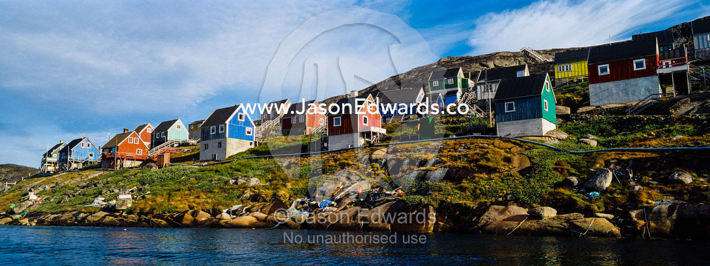 Colorful fishing houses perched on the rocky shoreline of an arctic island. Kangaamiut, Gammel Sukkertoppen, Qeqqata Municipality, Greenland.