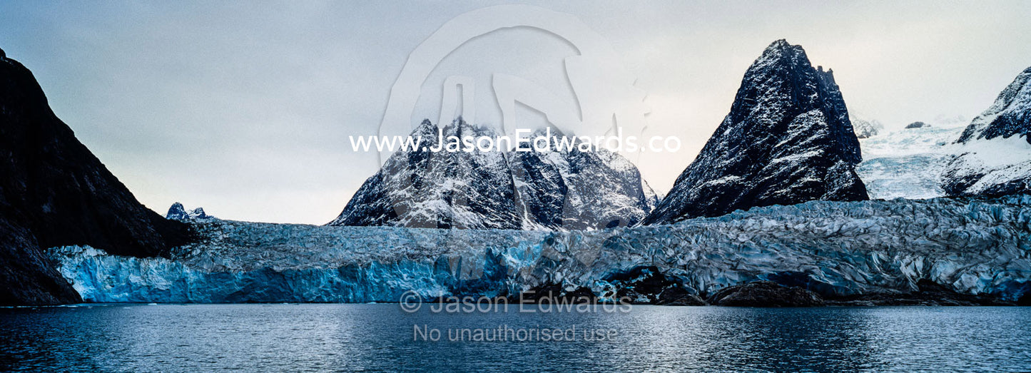 The sheer fracture zone of a glacier sandwiched between alpine peaks in a fjord. Fjord of Eternity, Maniitsoq, Sukkertoppen, Qeqqata Municipality, Greenland.