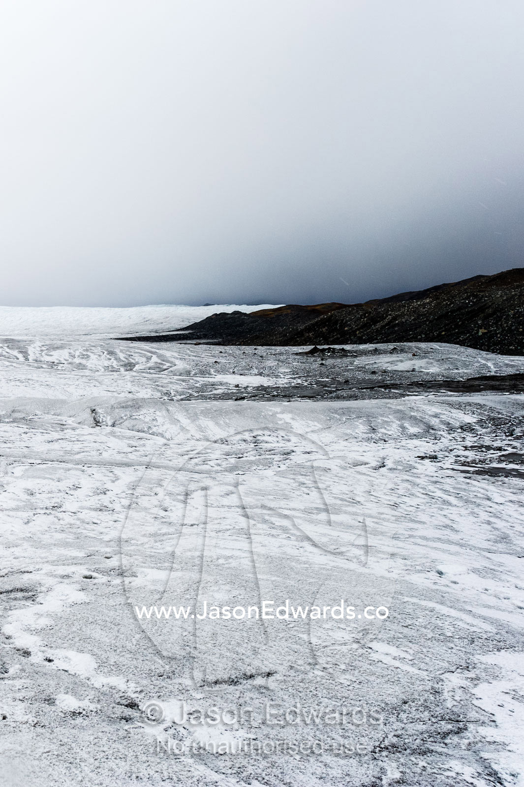 A barren, icy wasteland where the Greenland Ice Sheet presses against a rocky shore. Isunngua Highland, Greenland Ice Sheet, Kangerlussuaq, Qeqqata Municipality, Greenland.