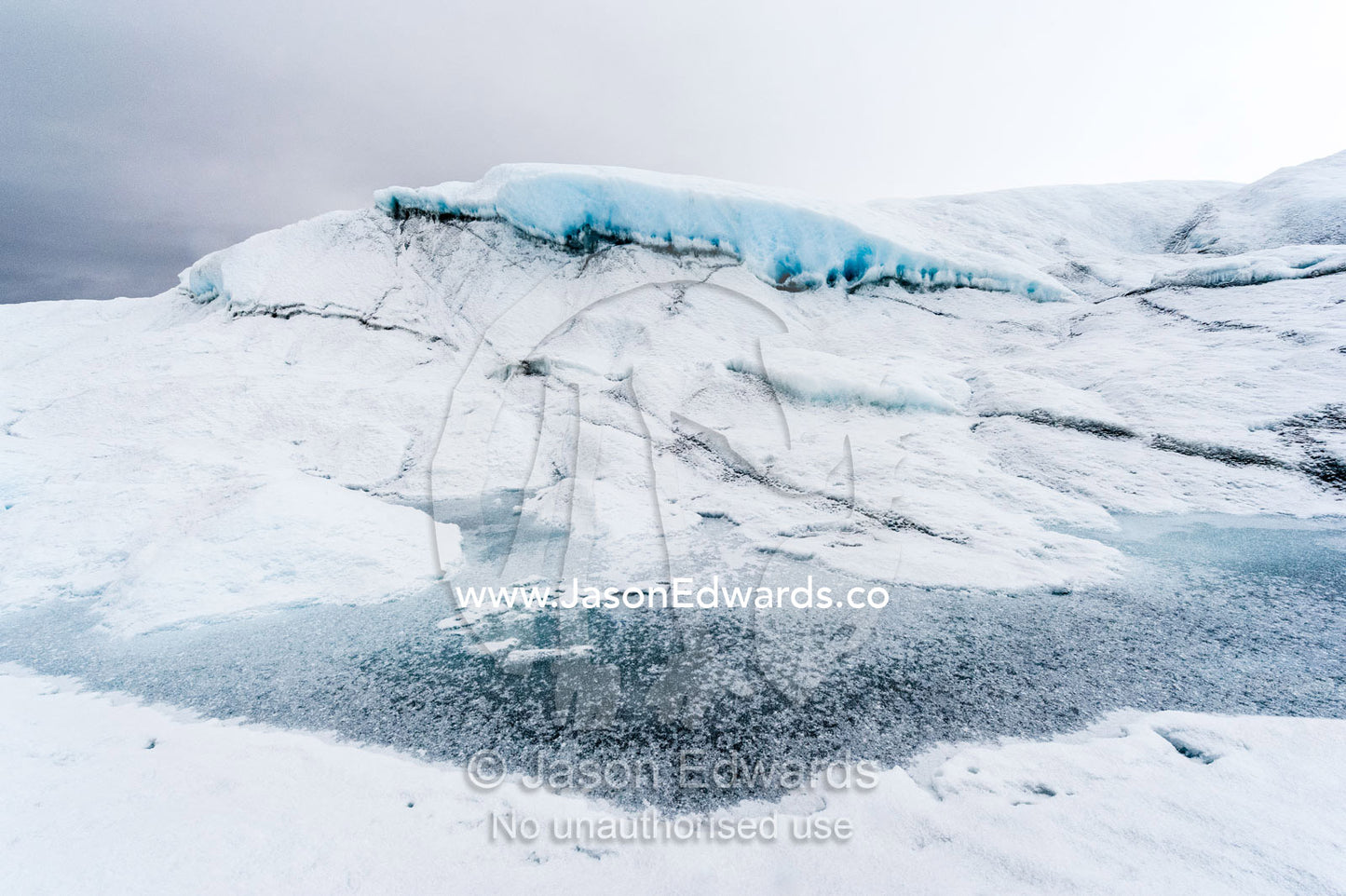 The frozen surface of a melt pond on the surface of the Greenland Ice Shelf. Greenland Ice Sheet, Qeqqata Municipality, Kangerlussuaq, Greenland.