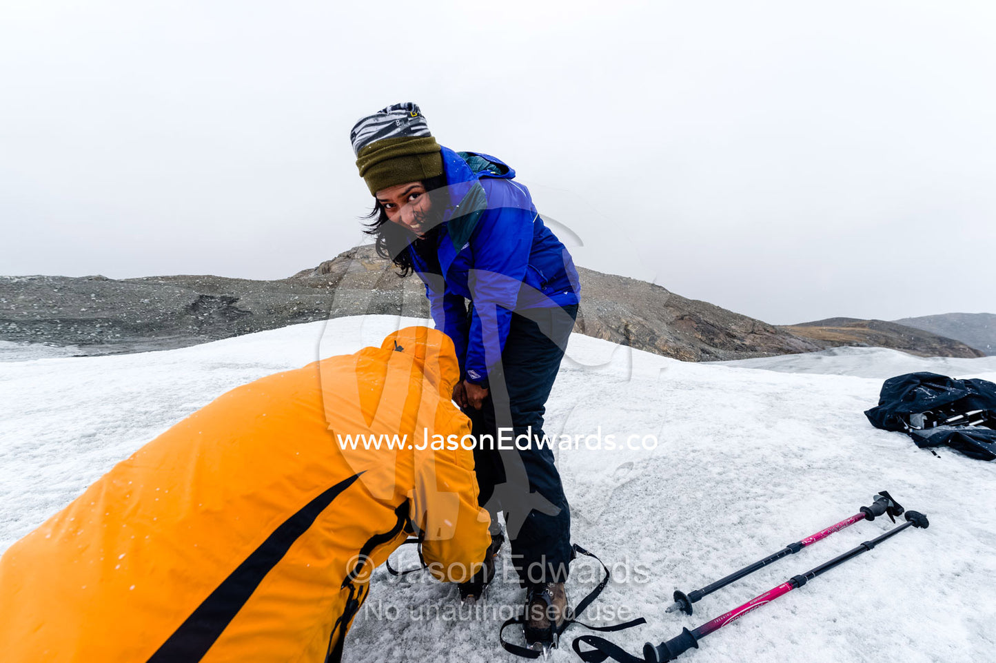 Tourist fitting crampons to their boots to hike on the Greenland Ice Shelf. Isunngua Highland, Greenland Ice Sheet, Kangerlussuaq, Qeqqata Municipality, Greenland.