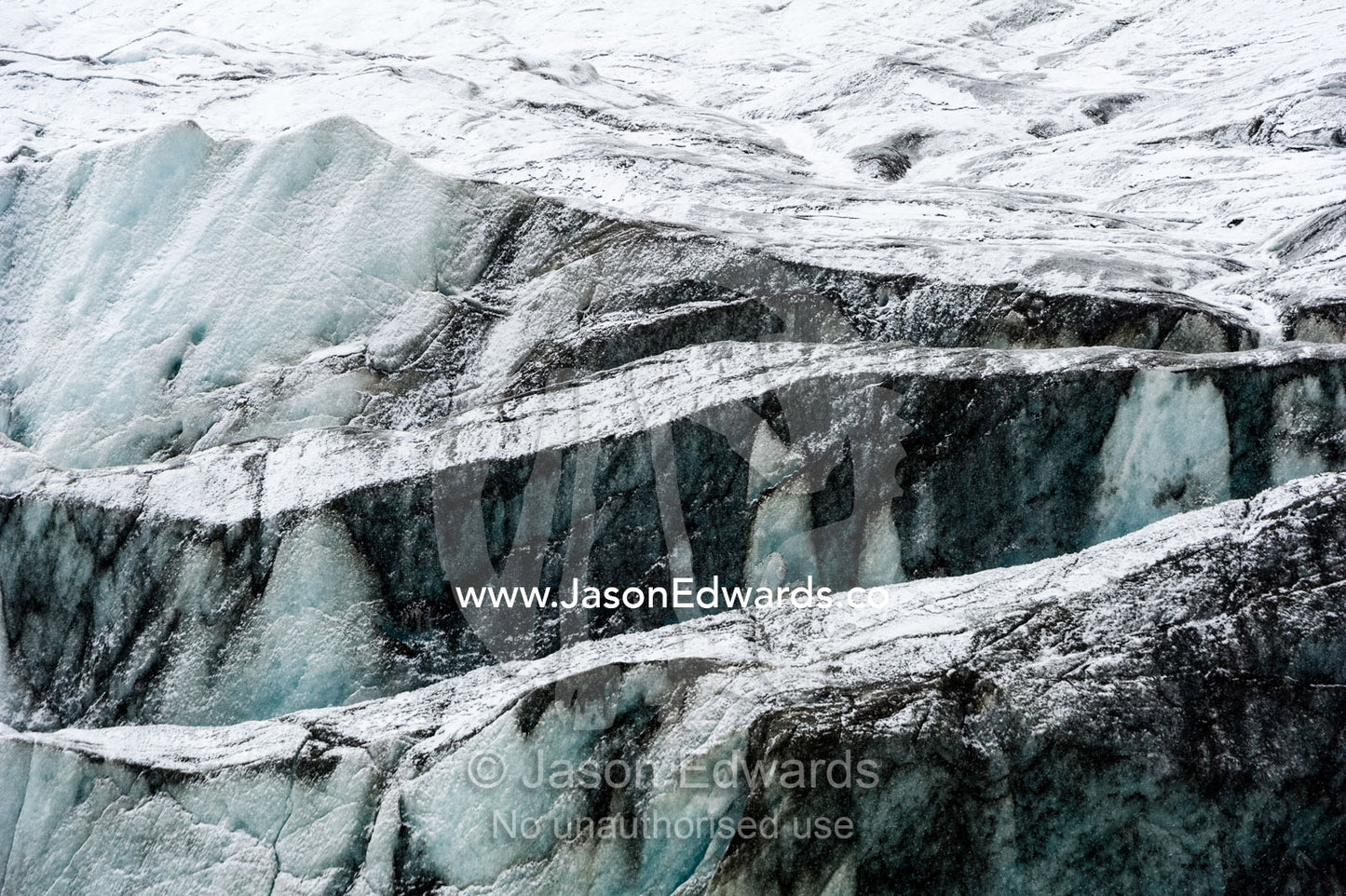 Silt and sediment darkens the surface of a glacier where it's eroding the surrounding rock. Greenland Ice Sheet, Qeqqata Municipality, Kangerlussuaq, Greenland.