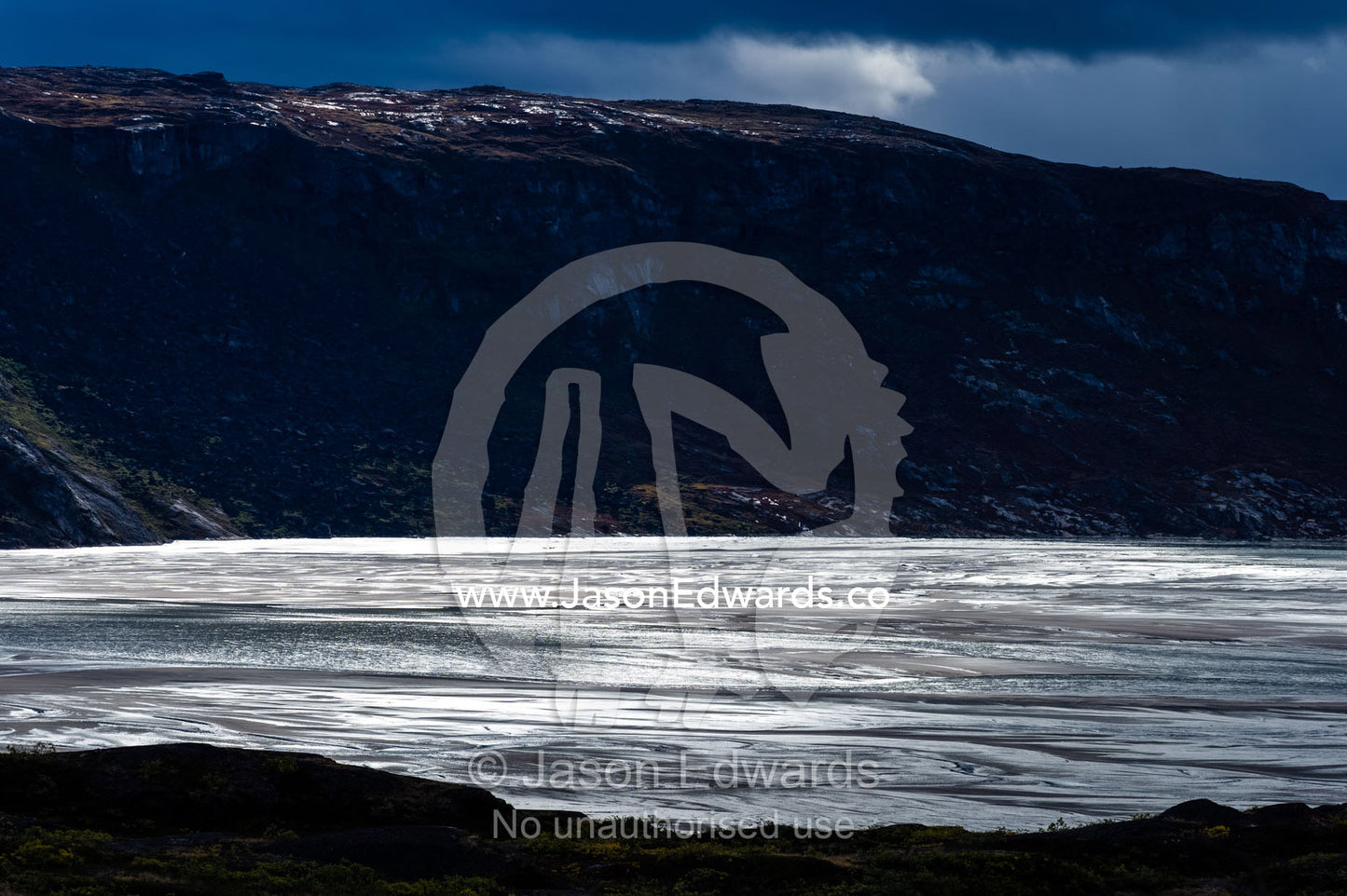 Sunrays illuminate a vast river floodplain carrying glacier run-off that creates quicksand plains. Kangerlussuaq Fjord, Kangerlussuaq, Qeqqata Municipality, Greenland.