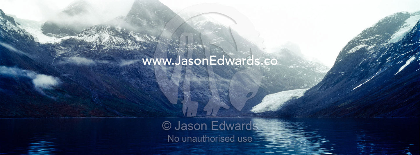 A jagged glacier tongue recedes up and rugged and inhospitable mountain gorge in a fiord. Fjord of Eternity, Maniitsoq, Sukkertoppen, Qeqqata Municipality, Greenland.