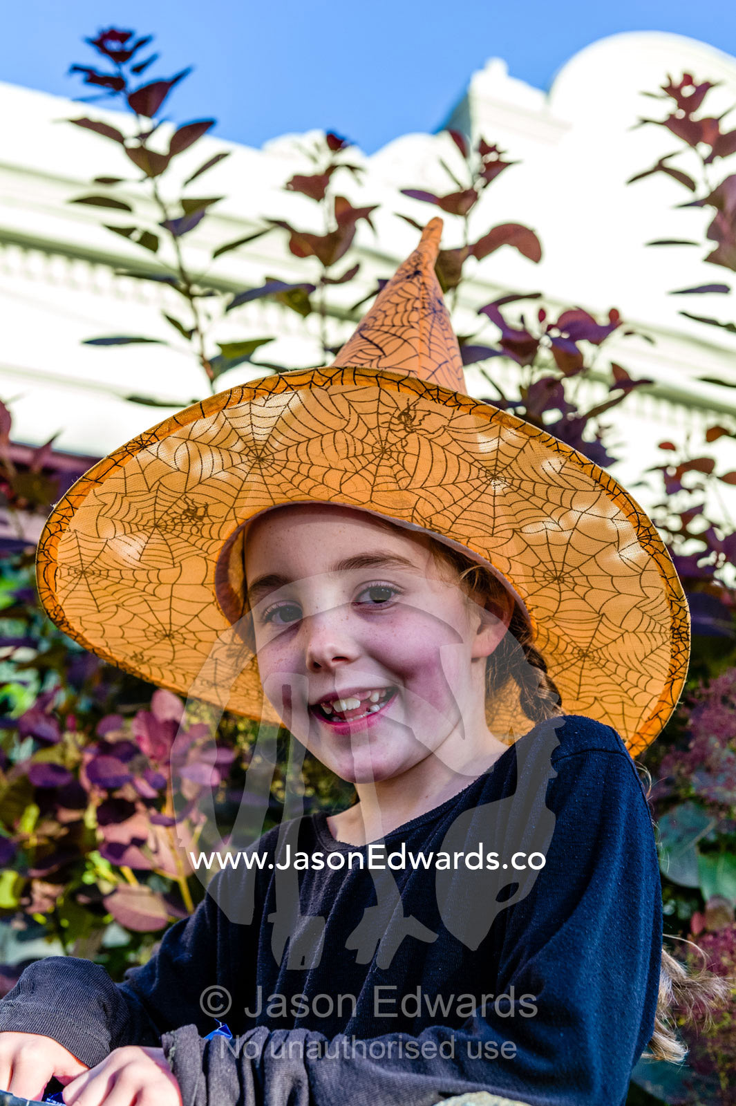 A girl dressed as a witch in a pointy orange hat on Halloween. Carlton North, Melbourne, Victoria, Australia.