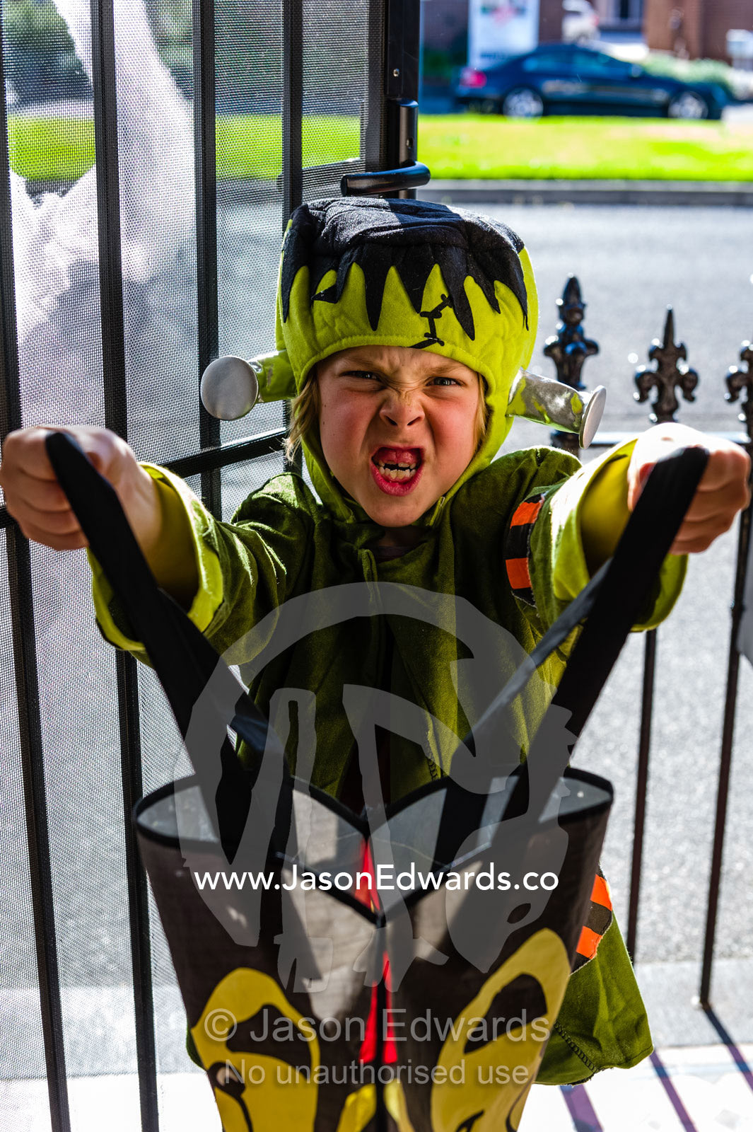 A boy dressed as Frankenstein demands candy during trick or treat on Halloween. Carlton North, Melbourne, Victoria, Australia.