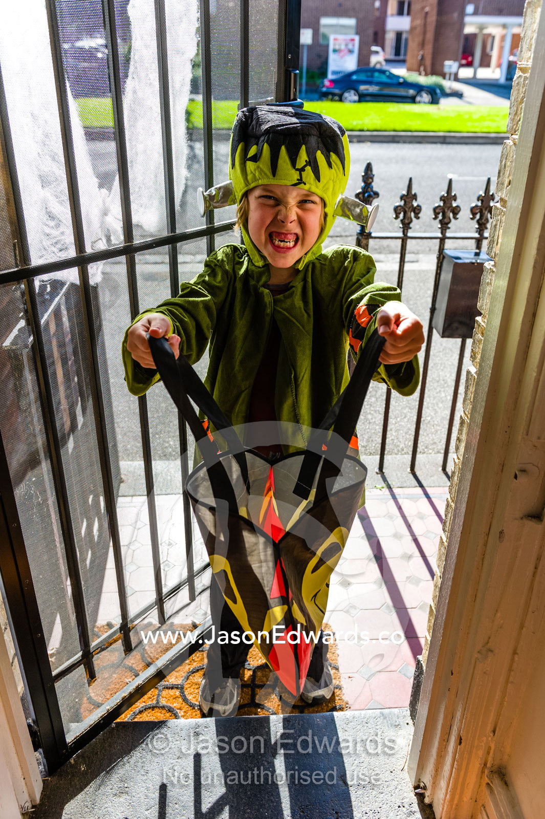 A boy dressed as Frankenstein demands candy during trick or treat on Halloween. Carlton North, Melbourne, Victoria, Australia.