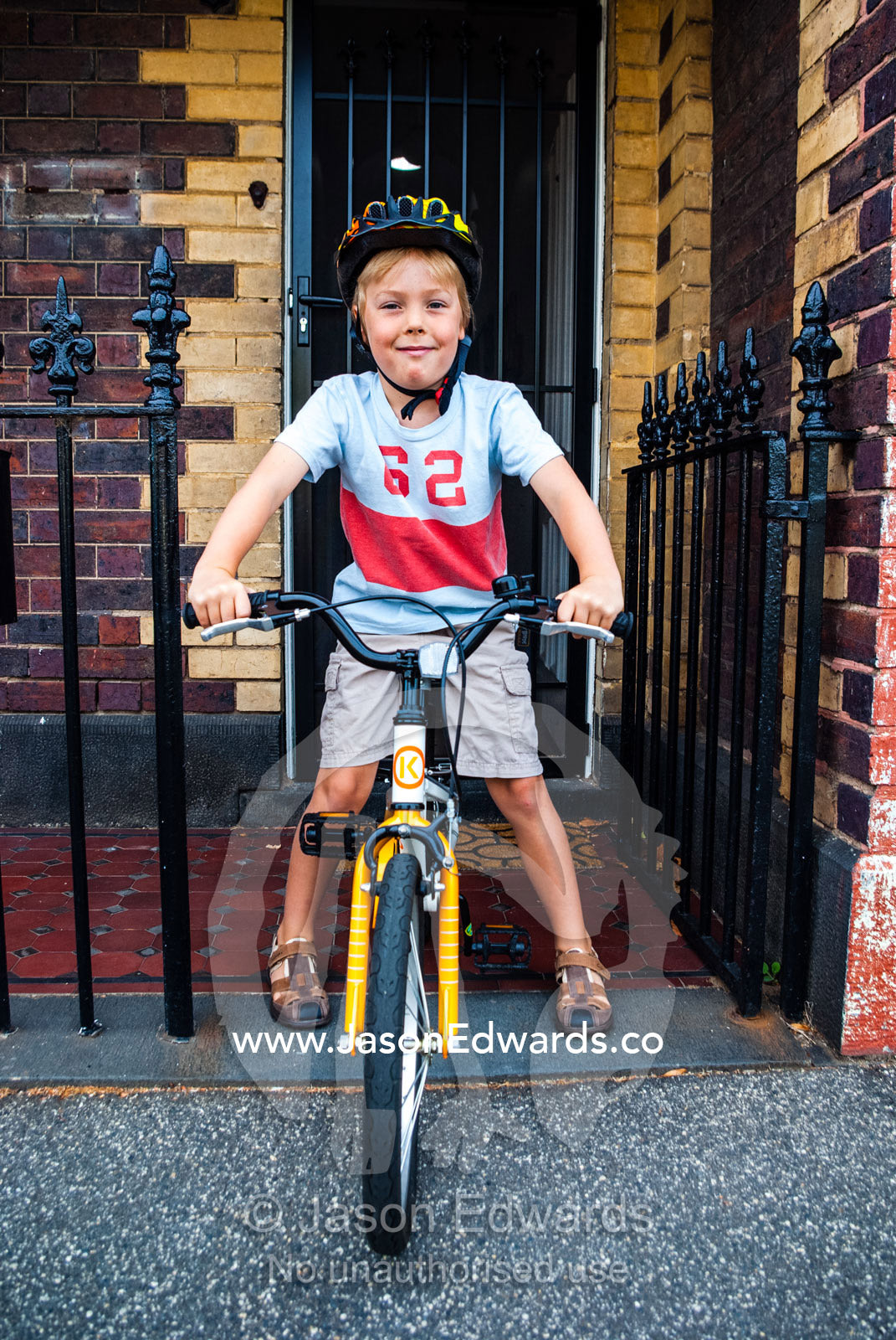 A boy prepares to ride his bike on the first day of school. Carlton North, Melbourne, Victoria, Australia.