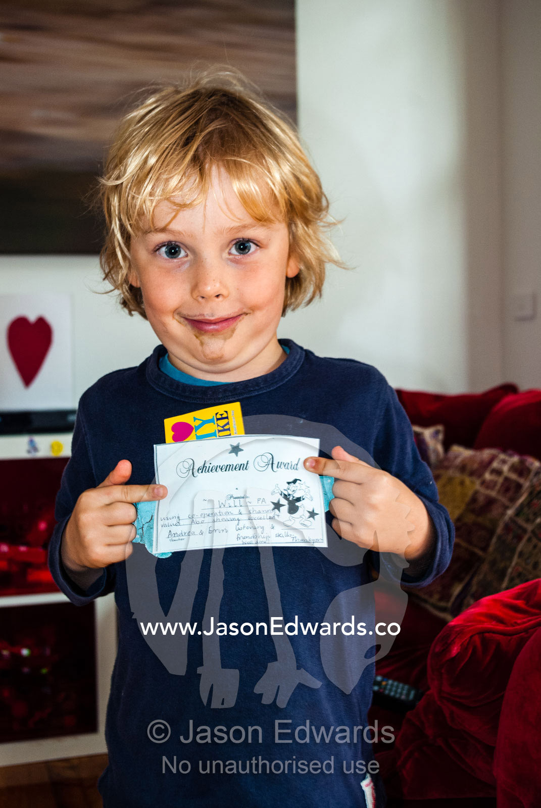 A small boy displays an award he received at school. Carlton North, Melbourne, Victoria, Australia.