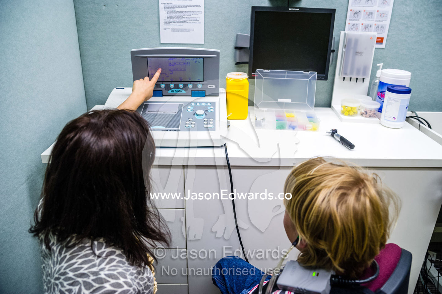 An audiologist teaches a boy about his hearing test results in a clinic. The University of Melbourne Audiology Clinic, Carlton, Melbourne, Victoria, Australia.