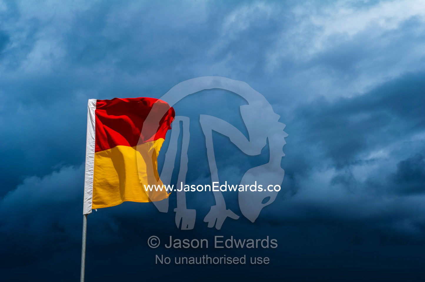 The red and yellow flag of a lifeguard patrol on a stormy beach. Yaroomba Beach, Queensland, Australia.