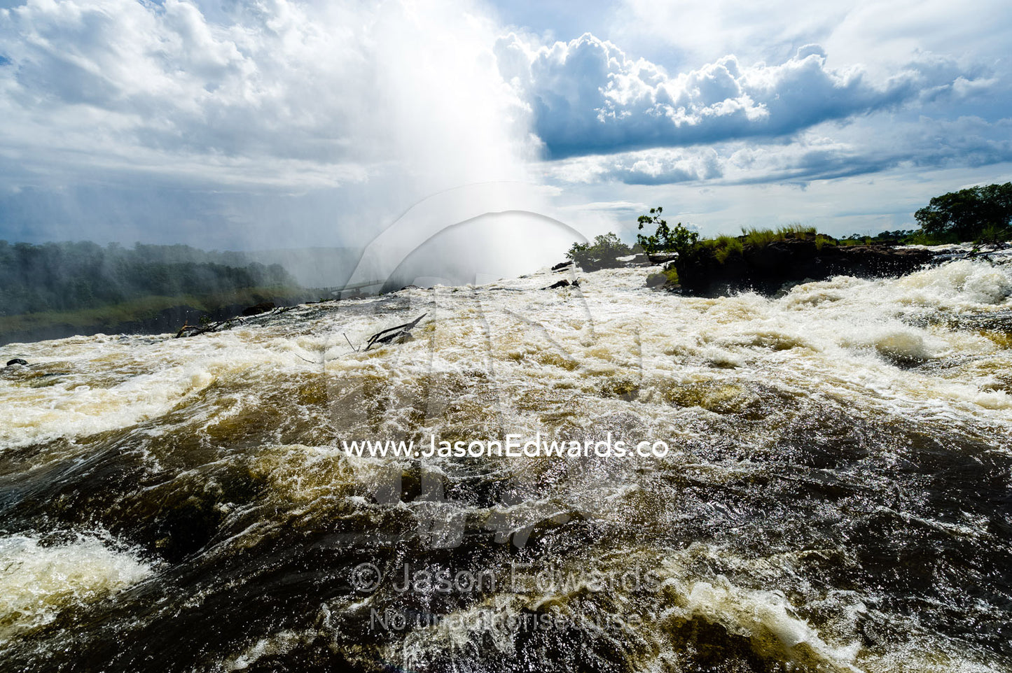 The rapids of the Zambezi River tumble over Victoria Falls sending up a plume of mist. Zambezi River, Victoria Falls, Mosi-oa-Tunya National Park, Zambia.