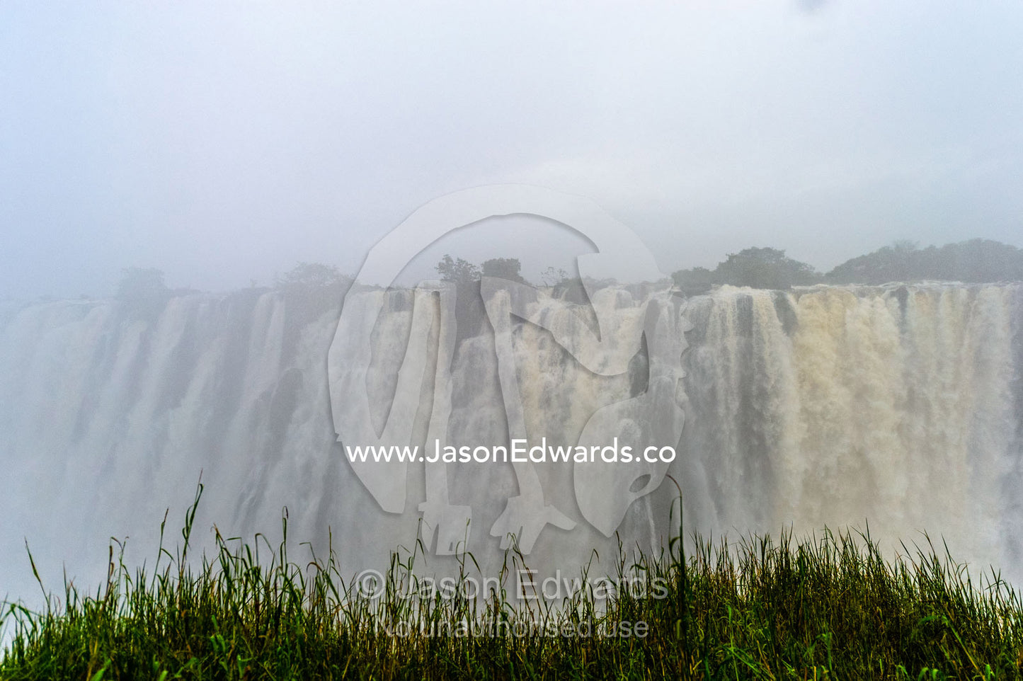 A rainstorm falls over the cascading Victoria Falls already in flood. Zambezi River, Victoria Falls, Mosi-oa-Tunya National Park, Zambia.