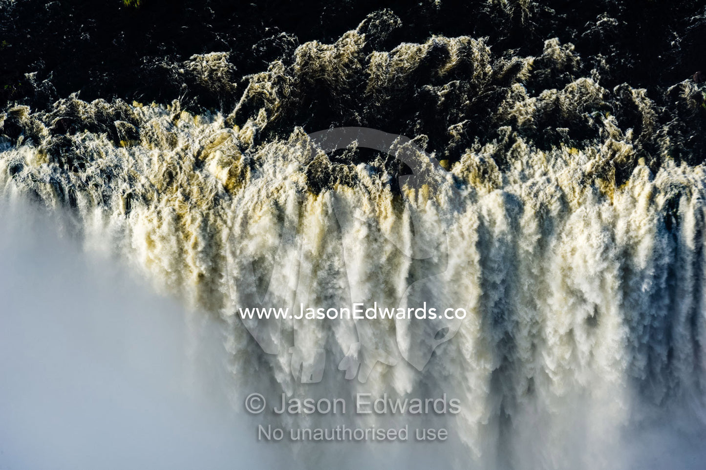 The flooded waters of the Zambezi River cascade in a curtain across the face of Victoria Falls. Zambezi River, Victoria Falls, Mosi-oa-Tunya National Park, Zambia.