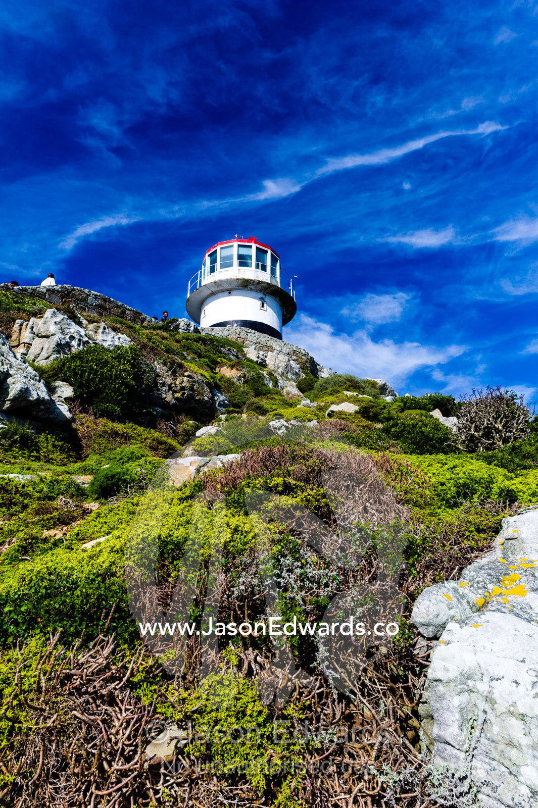 An antique lighthouse summits a cliff near the Cape of Good Hope. Cape of Good Hope, Cape Point, Table Mountain National Park, Cape Peninsula, South Africa.