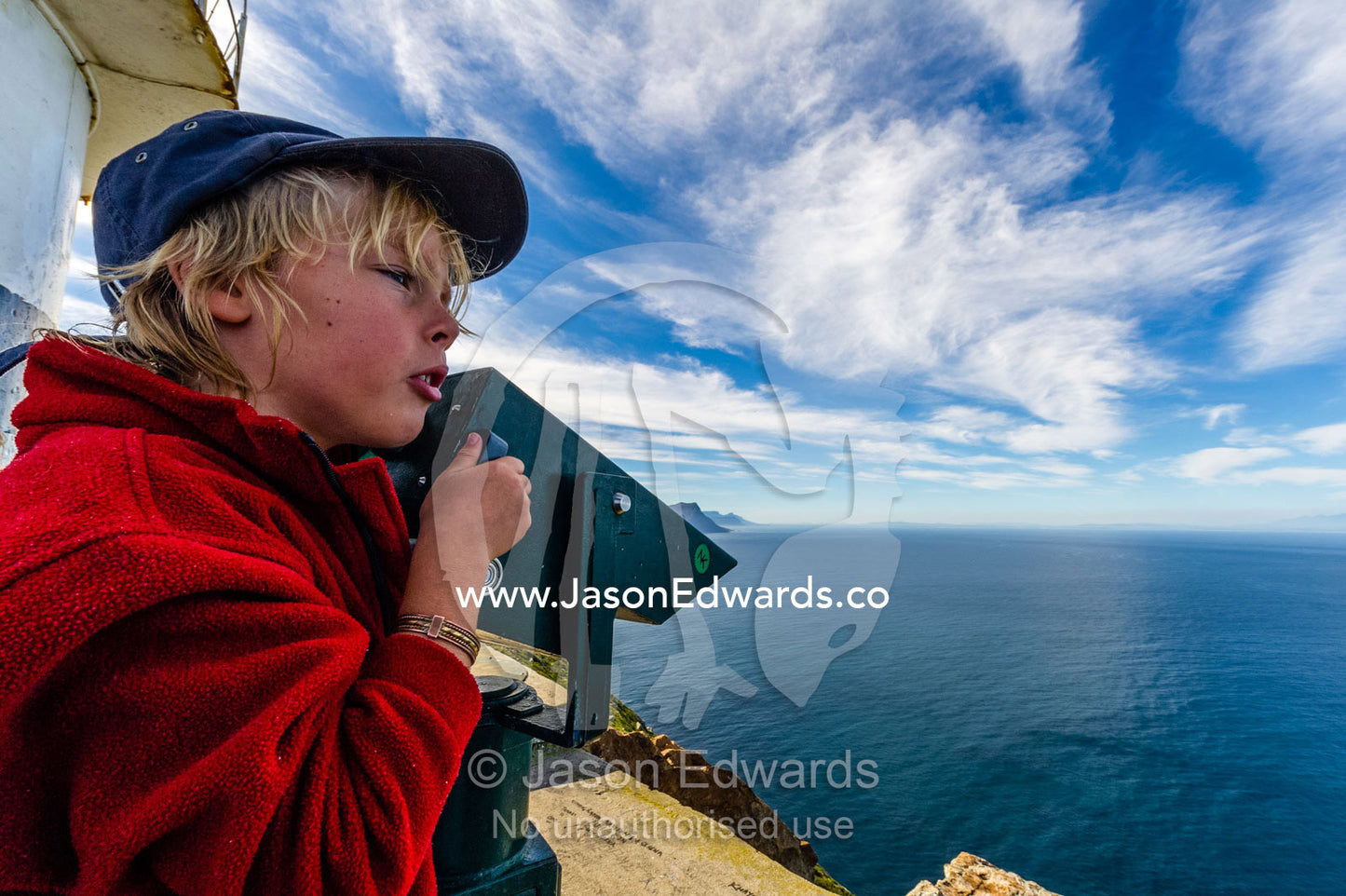 A boy searching the ocean through coin operated binoculars on a lighthouse. Cape of Good Hope, Cape Point, Table Mountain National Park, Cape Peninsula, South Africa.